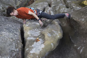 Young man climbs on a cliff with a rope.