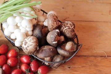 Mushrooms and vegetables on wood background.
