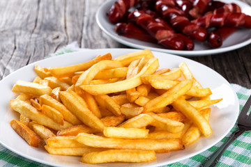 Tasty french fries on plate, on wooden table background