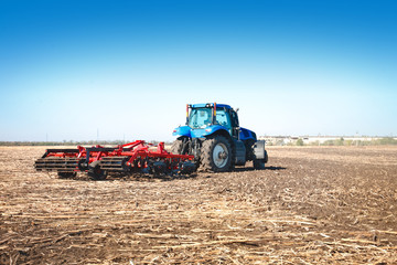 Obraz premium Blue tractor working in an open field