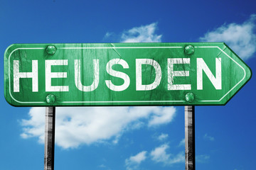 Heusden road sign, vintage green with clouds background