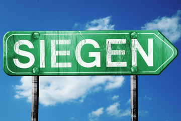 Siegen road sign, vintage green with clouds background