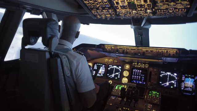 Dramatic angle from rear of 747 cockpit as African American pilot makes a long turn over an area of northern California, USA.  Stabilized hand-held camera, medium shot, recorded in 4K at 30ps.