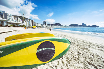 Braziliaanse vlag opstaan paddle surfplanken gestapeld op het strand van Copacabana, Rio de Janeiro Brazilië