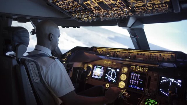 Dramatic side view of 747 cockpit as African American pilot makes a long turn over an area of northern California, USA.  Stabilized hand-held camera, with rack focus from exterior to interior.