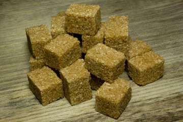 Cubes brown cane sugar on wooden background