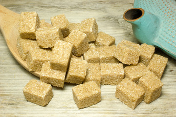 Cubes brown cane sugar on wooden background
