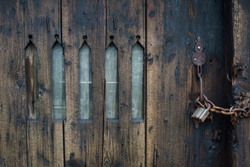 Padlocked chain, locked wooden door with arched window slits to an farm outhouse in castleton, Derbyshire.
