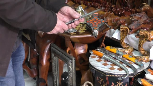 Tourist looking at Moroccan ornamental dagger in the souvenir shop at the market in  Morocco