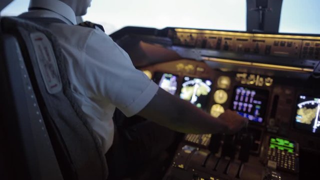 Rear angle view over pilot's shoulder as he takes off in a jumbo jet.  Hand-held camera, medium close, with tilt from throttles to windows, originally recorded in 4K at 30fps.