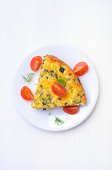 Vegetable omelet on the plate on a white table, top view