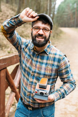 Young man bearded with film photocamera in the forest