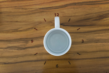 Cup of coffee and clock concept on wooden table