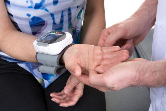 Doctor taking young man's blood pressure at clinic