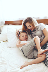 Obraz premium Mother plays with son in bed