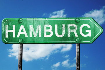 Hamburg road sign, vintage green with clouds background