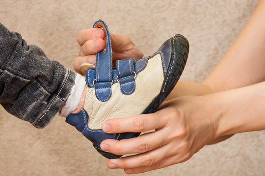 hands of mother helping her child to put shoes