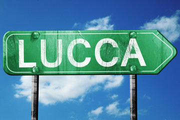 Lucca road sign, vintage green with clouds background