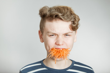 Handsome boy with a mouthful of grated carrot