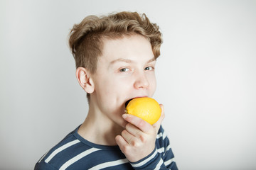 Young boy about to bite a fresh lemon