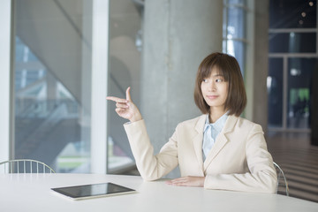 Attractive asian business woman showing something on workplace