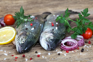 Fresh trouts with spices and seasoning on rustic board