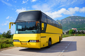 Fototapeta premium Empty touristic bus is standing on the road near the mountain