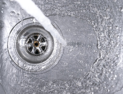 Running water drains down a stainless steel sink