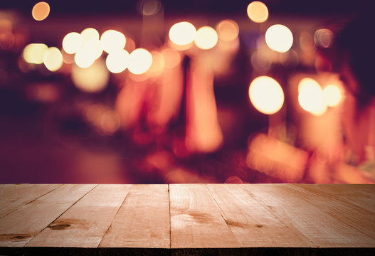 wooden table in front of abstract blurred lights in bar