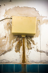 Old broken flushing mechanism against a damaged plaster wall