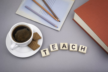 Text: Teach from wooden letters on a gray desk