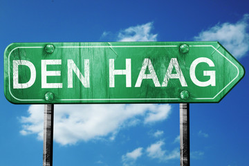 Den haag road sign, vintage green with clouds background