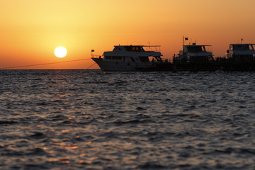 Fototapeta premium Sunrise at Pier with calm sea water and three yachts