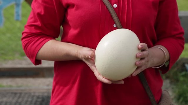 Woman holding an ostrich egg in her hands.
