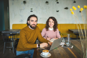 Young hipster male and female working laptop together in cafe