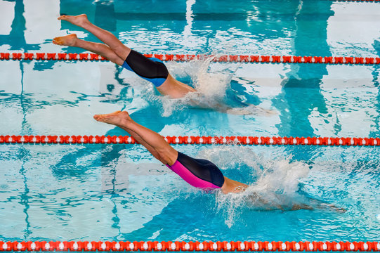 Swimmers jumping to water in a pool.