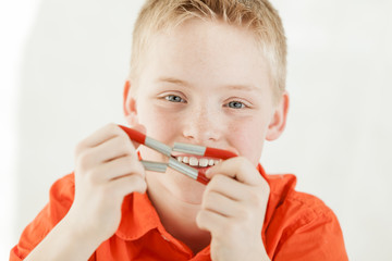 Cheerful boy holds magnets together by his face