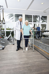 Physiotherapist Assisting Woman With Walker In Rehab Center