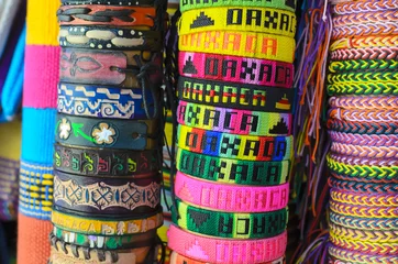 Tuinposter Numerous colorful wristbands with Oaxaca sight for sale at craft market  © Alice Nerr