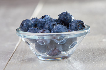 Fresh blueberries with water drops in a glass bowl