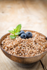 Buckwheat porridge in a bowl with mint leaves and blueberries.