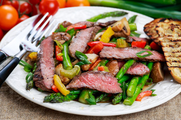 Grilled steak with stir-fried vegetables on plate.