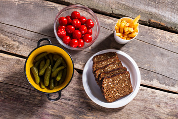 Bread with fries and tomatoes. Pickles and bread on table. Fresh vegetables and brown bread. Ingredients for breakfast.