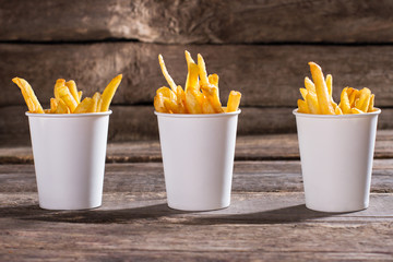 French fries in cups. Cups of fries on table. Standard portions of snack. Well-made fries in cafe. - Powered by Adobe