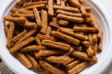 Small cracker sticks on plate. Bread crackers on white plate. Simple homemade appetizer. Crackers served in cafe.