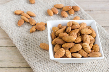 Almonds in a white bowl on a wooden table