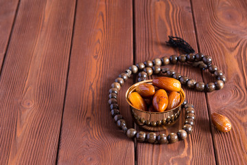 Dates fruit and rosary still life, on a brown wooden background