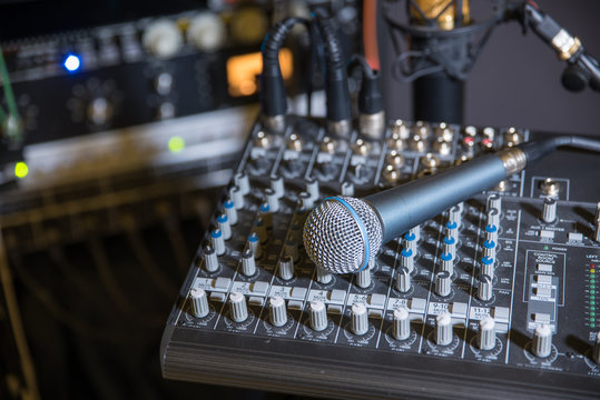 Mixing console and dynamic microphone in recording studio setting.