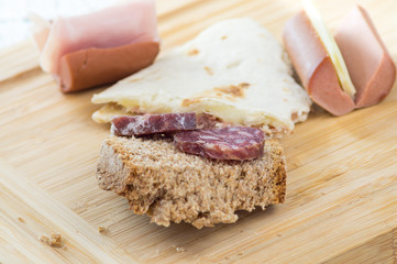 Piadina romagnola, salame formaggio e wurstel in primo piano, antipasto stuzzichini