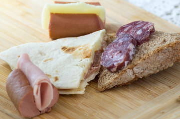 Piadina romagnola, salame formaggio e wurstel in primo piano, antipasto stuzzichini